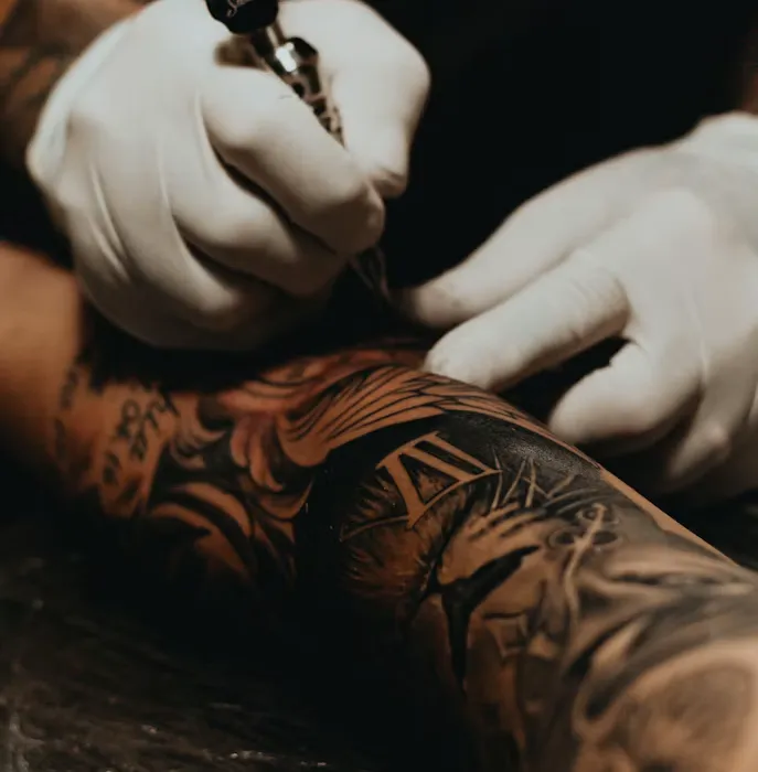 Intricate detail of tattoo machine inking a mandala pattern on skin
